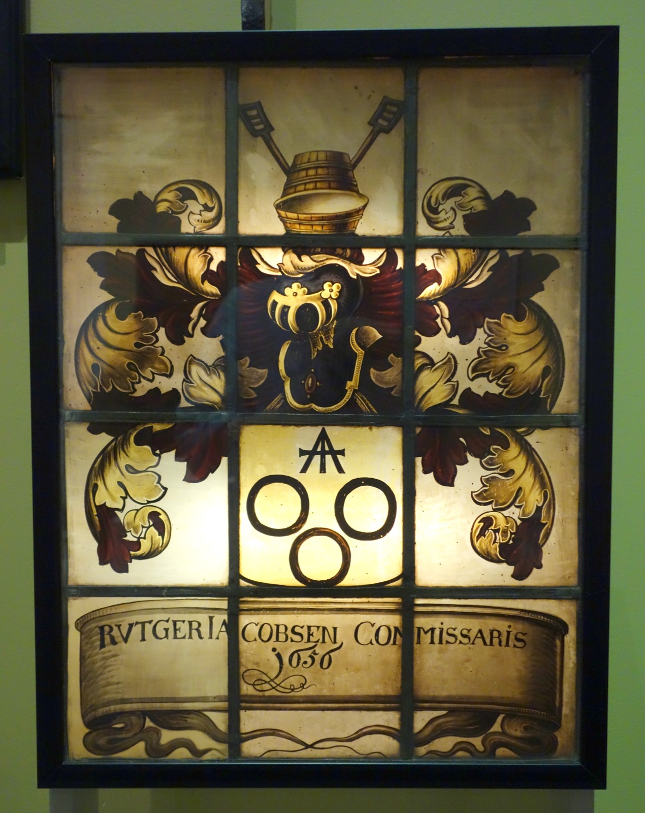 Leaded stained-glass window with a family crest showing brewing tools